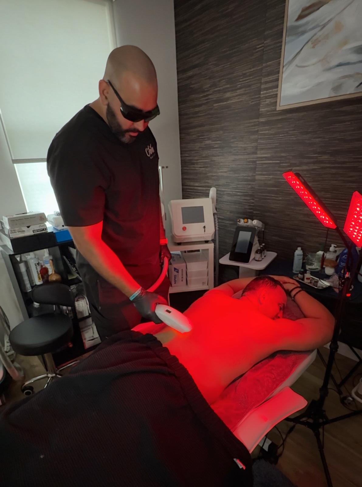 Male client receiving laser hair removal on back at Cibibe Beauty & Health using red light diode equipment.